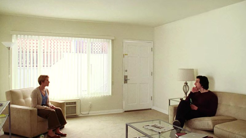 Duas pessoas sentadas em uma sala, cada uma, em um sofá.