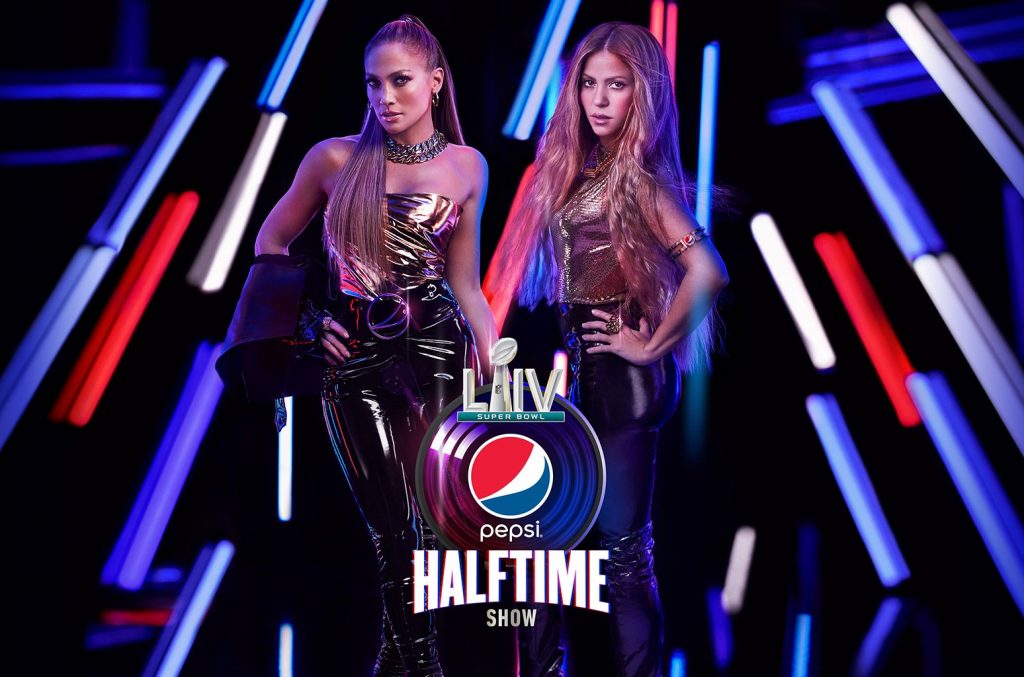 Jennifer Lopez e Shakira, em uma iluminação de fundo coma s cores que representam a marca da Pepsi, patrocinadora do evento.