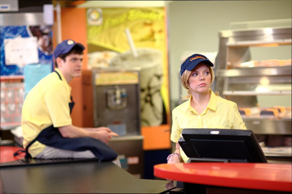 Dois funcionários de um fast food olhando para o lado