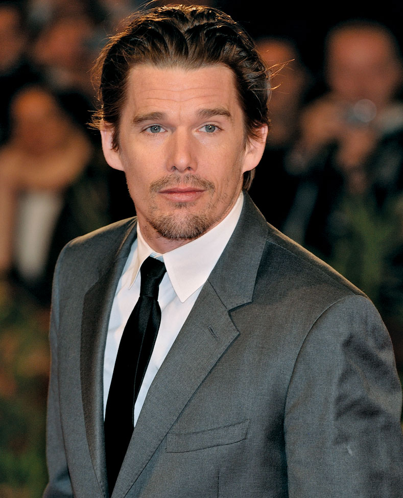 Ator Ethan Hawke, de 50 anos, em um terno cinza e gravata preta. Ele possivelmente será vilão de Cavaleiro da Lua.