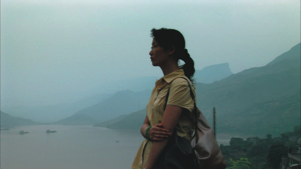 Mulher ao lado de um rio e muita neblina, cena do filme em busca da vida. 