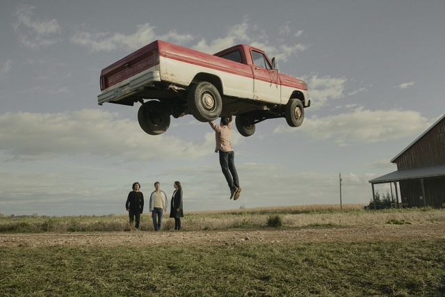 A foto mostra o ator Tyler Hoechlin como Clark Kent levantando uma camionete ao lado de seus filhos adolescentes 
