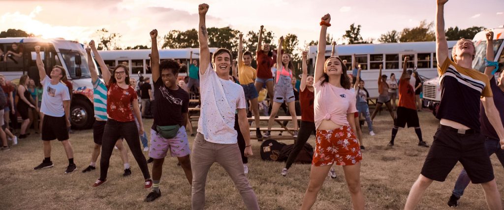 Grupo de jovens dançam coreografia em um acampamento