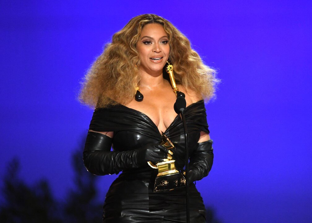 A cantora Beyonce com um vestido de couro preto segurando o grammy que venceu. Otageek