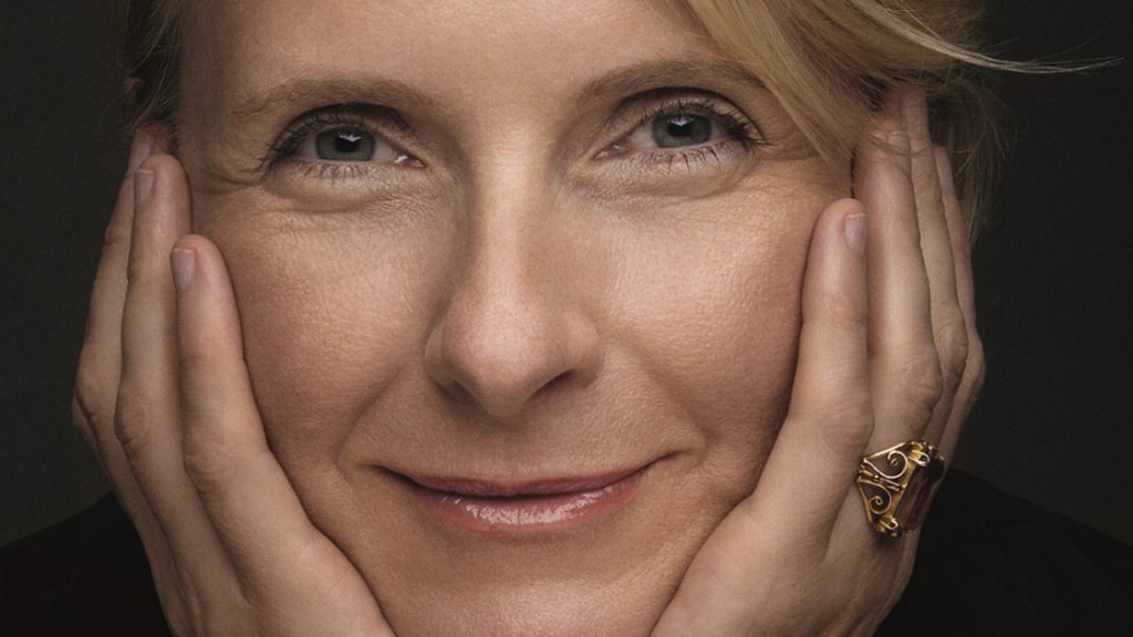 Retrato da autora Elizabeth Gilbert com as mãos no rosto. Cidade das Garotas. Otageek.