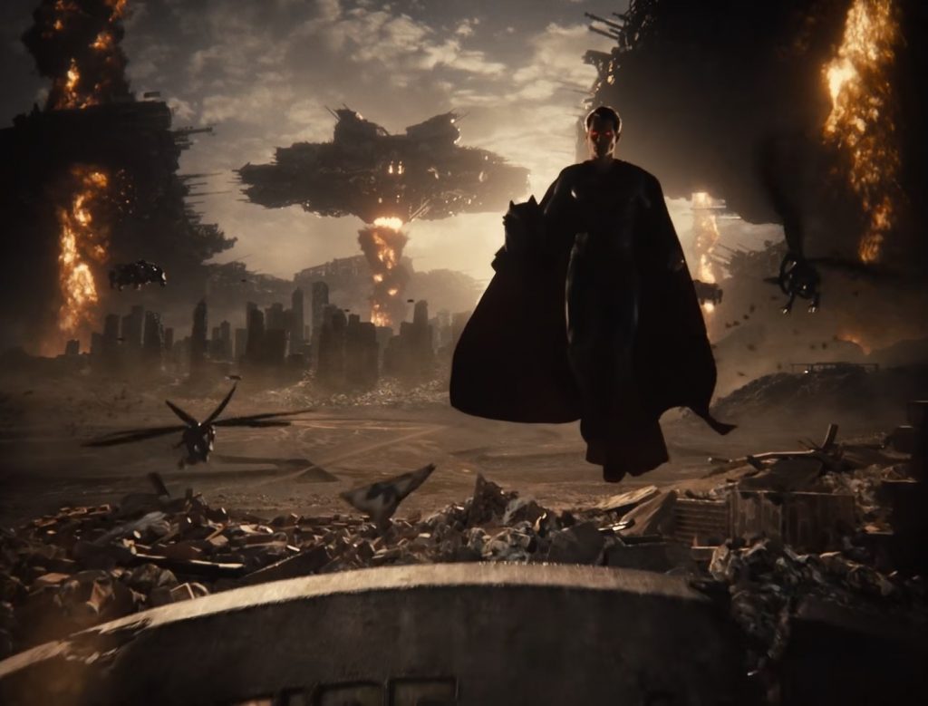 Superman paira numa paisagem apocalíptica segurando o elmo de Batman enquanto naves alienígenas e parademônios voam ao fundo.