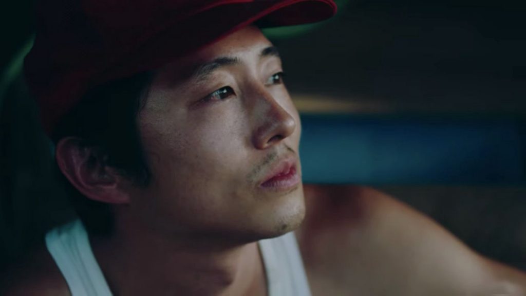 Foco no rosto do ator, Steven Yeun, olhando para frente em cena de Minari.