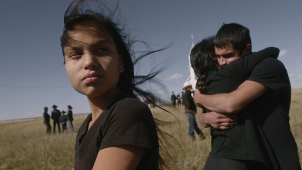 Jashuan, John, a mãe deles e outros moradores de Pine Ridge no terreno de uma igreja no filme Songs My Brothers Taught Me