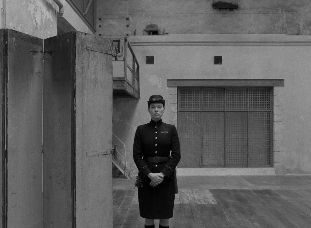 imagem em preto e branco de uma mulher com trajes militares e expressão séria ao centro em A Crônica Francesa - Otageek