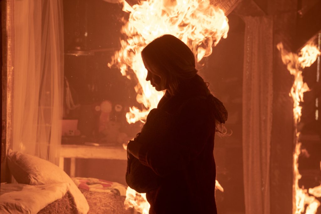 Cena do filme "Um Lugar Silencioso - Parte II". Na imagem, vemos Evelyn, personagem de Emily Blunt, dentro de uma casa em chamas, carregando em seu colo um bebê.