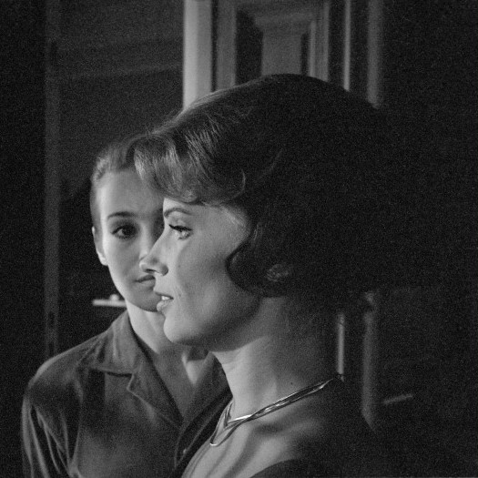 Imagem em preto-e-branco do filme "O Silêncio" (1963), de Ingmar Bergman. Nela, vemos as irmãs Ester e Anna. Ester está ao fundo, de frente para a câmera, enquanto Anna está em primeiro plano, de perfil. 