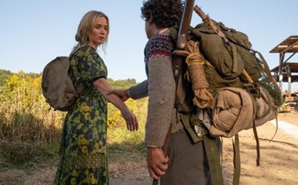 Evelyn, interpretada por Emily Blunt, com seu filho Marcus segurando o seu braço parados na estrada - otageek