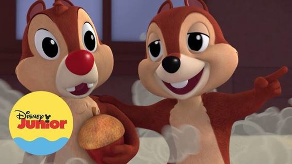 Imagem promocional de "Mickey Aventura Sobre Rodas". Nela, vemos os dois esquilos, Tico e Teco, em animação 3D. Um deles segura uma noz. No canto inferior esquerdo há um logo do canal Disney Junior, no formato de um selo azul e amarelo.