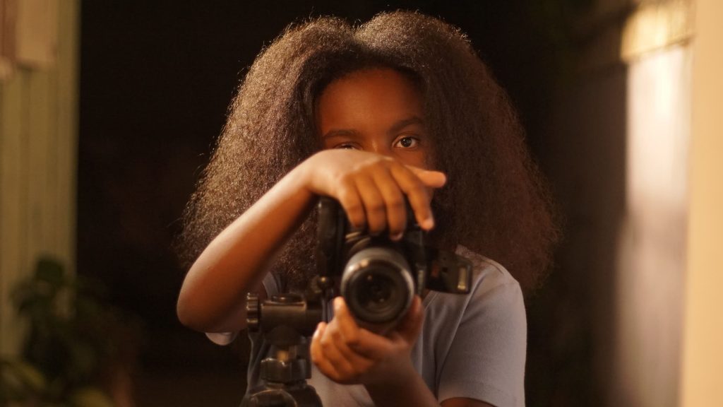 Menina com maquina fotográfica em mãos no curta baile