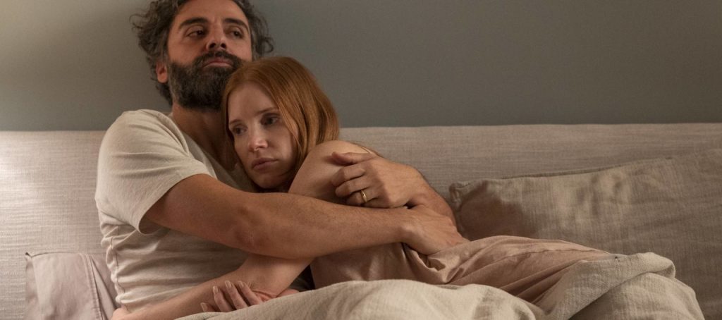 Imagem promocional da minissérie Cenas de um Casamento. Nela, vemos Jonathan (Oscar Isaac) abraçando Mira (Jessica Chastain). Ambos estão em um quarto, com tons pastéis, e aparentam estar deitados em uma cama.