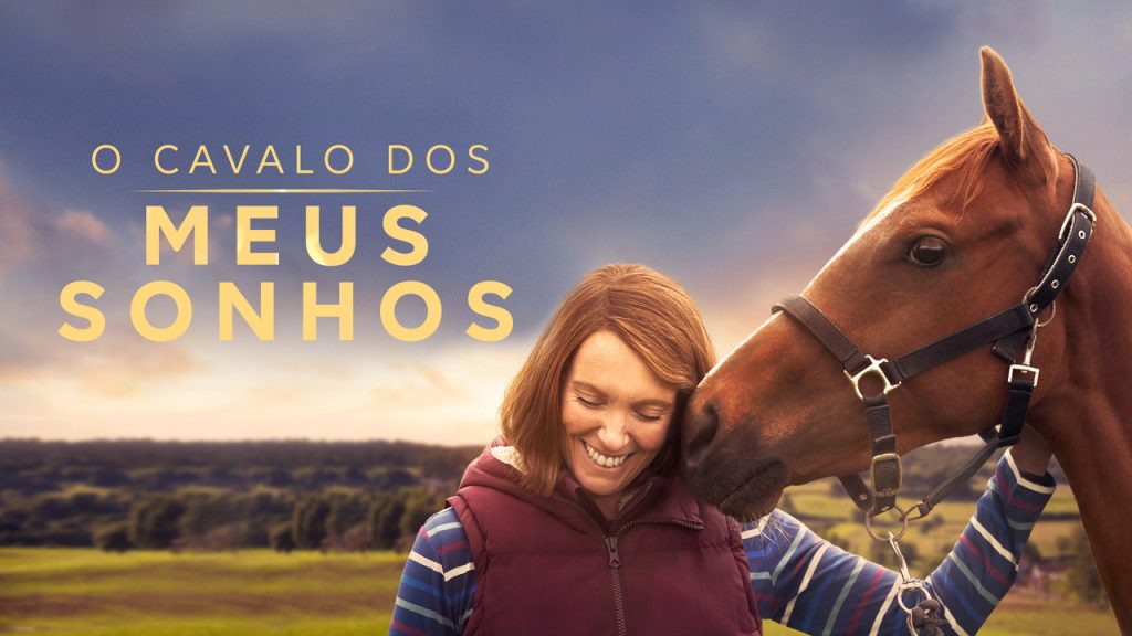 Imagem promocional do filme "O Cavalo dos Meus Sonhos". Nela, vemos à esquerda, em letras maiúsculas amarelas, o título do filme, e, à direita, a personagem Janet Volkes, de cabeça baixa, mas sorrindo, enquanto faz carinho em seu cavalo, Dream Alliance. Janet usa blusa comprida listrada multicolorida e um colete vermelho. Dream Alliance é um cavalo todo marrom.