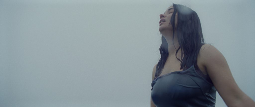 Uma mulher está chorando na chuva, molhada. Vestida com um vestido azul. Essa imagem pertence ao filme O Dia que Mudou o Mundo