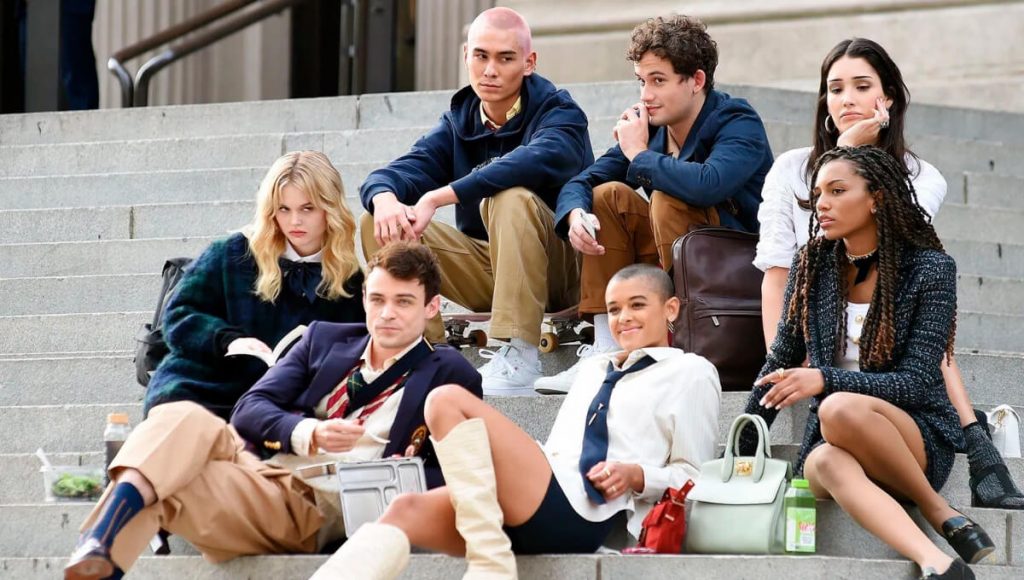 Atores jovens de Gossip Girl reunidos com uniforme escolar, sentados em uma escada - Otageek