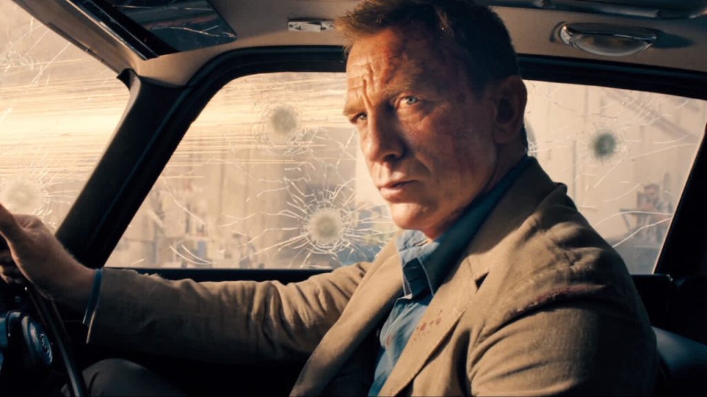 James Bond em seu carro blindado, com marcas de bala por toda a parte.