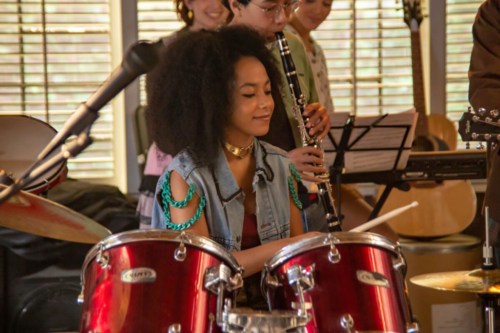 Em imagem oficial de Clube dos Graves, menina toca bateria numa sala de música