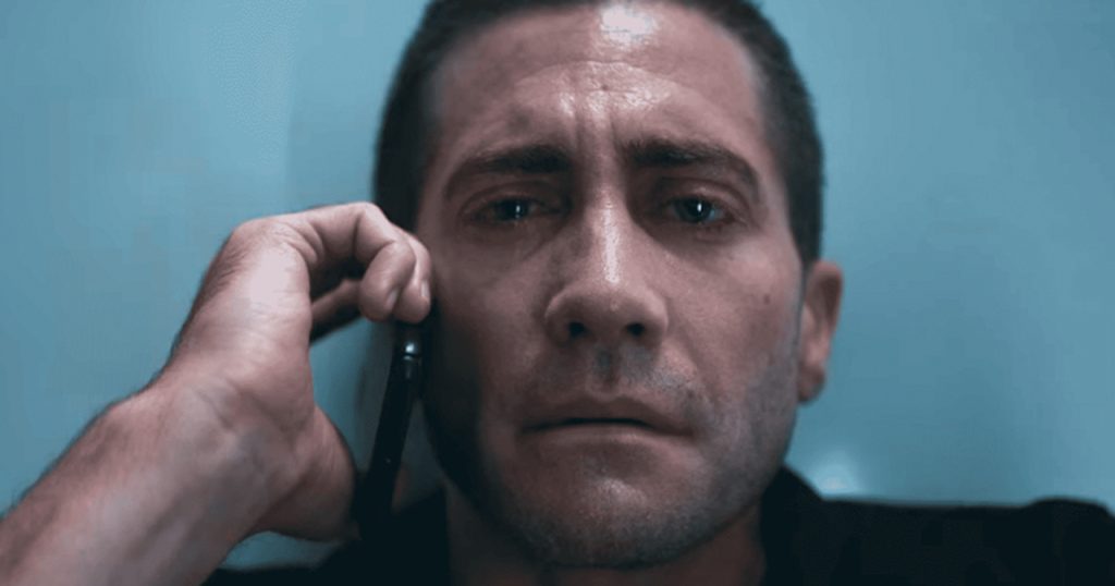 Jake Gyllenhaal segurando o telefone chorando em cena do filme O Culpado.