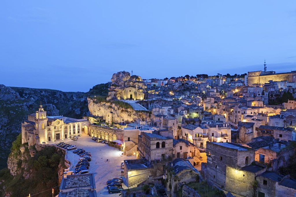 Paisagem italiana que conta com uma pequena cidade no alto de uma montanha, com arquiteturas clássicas e bem preservadas.