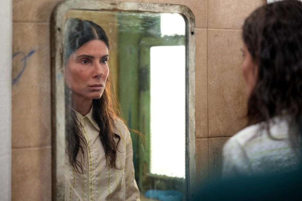 Uma mulher com a feição reflexiva olhando seu reflexo no espelho