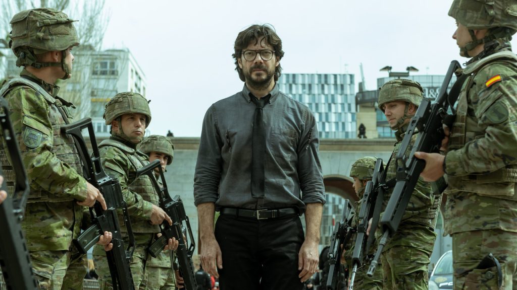 Imagem promocional da série "La Casa de Papel". Nela, vemos o personagem Professor em meio a duas fileiras de militares.