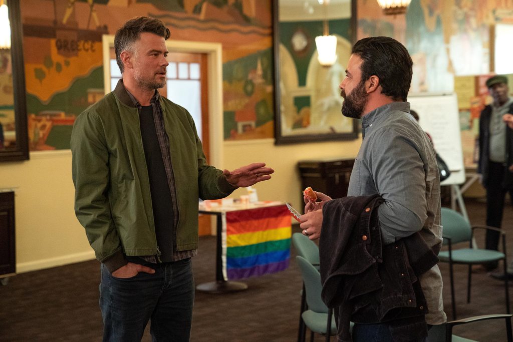 Imagem promocional da série Love Victor. Nela, vemos dois homens em pé, aparentemente discutindo, em uma sala de aula e, ao fundo, entre eles, há a bandeira LGBTQIA+