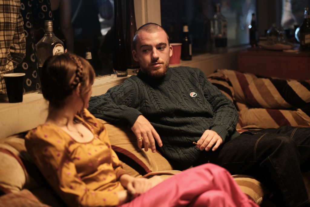 Cena de Lexi (Maude Apatow) e Fezco (Angus Cloud) no primeiro episódio da segunda temporada de Euphoria, onde mostra os dois persponagens conversando sentados em um sofá.