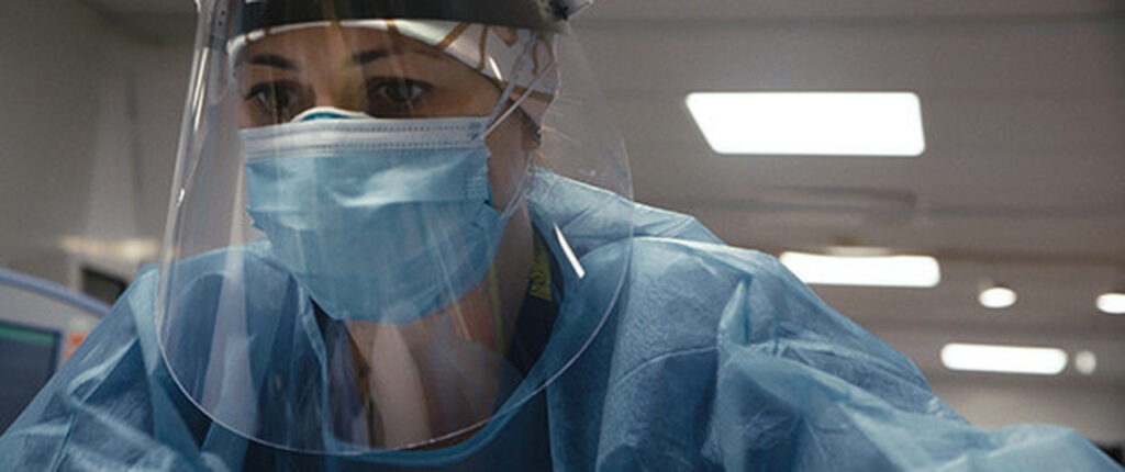 Cena do documentário sobre pandemia mostra uma médica com as máscaras cirúrgicas e o escudo facial necessário para se proteger do vírus da Covid-19.