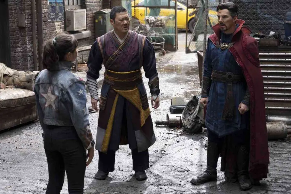 America Chavez, Wong e Doutor Estranho conversando em um beco