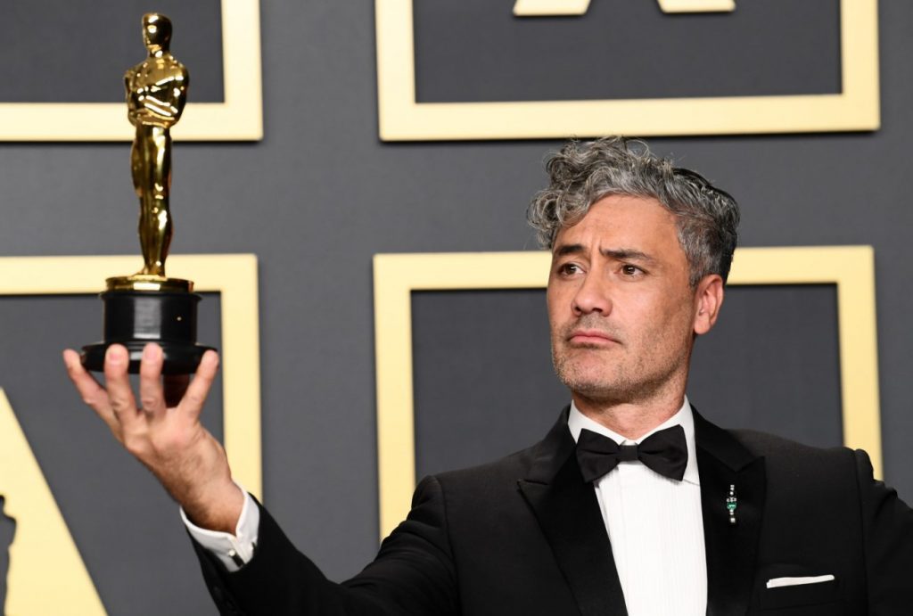 Taika Waititi segurando uma estátua do Oscar.